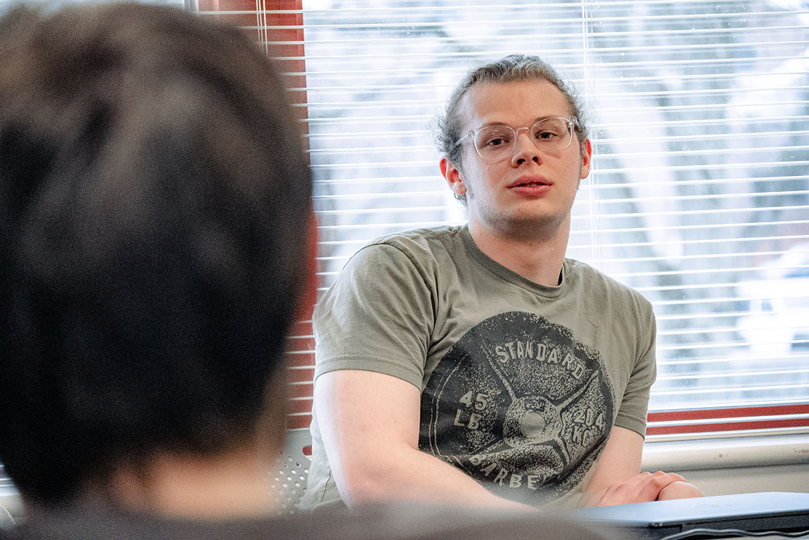 A college student wearing glasses takes part in a discussion